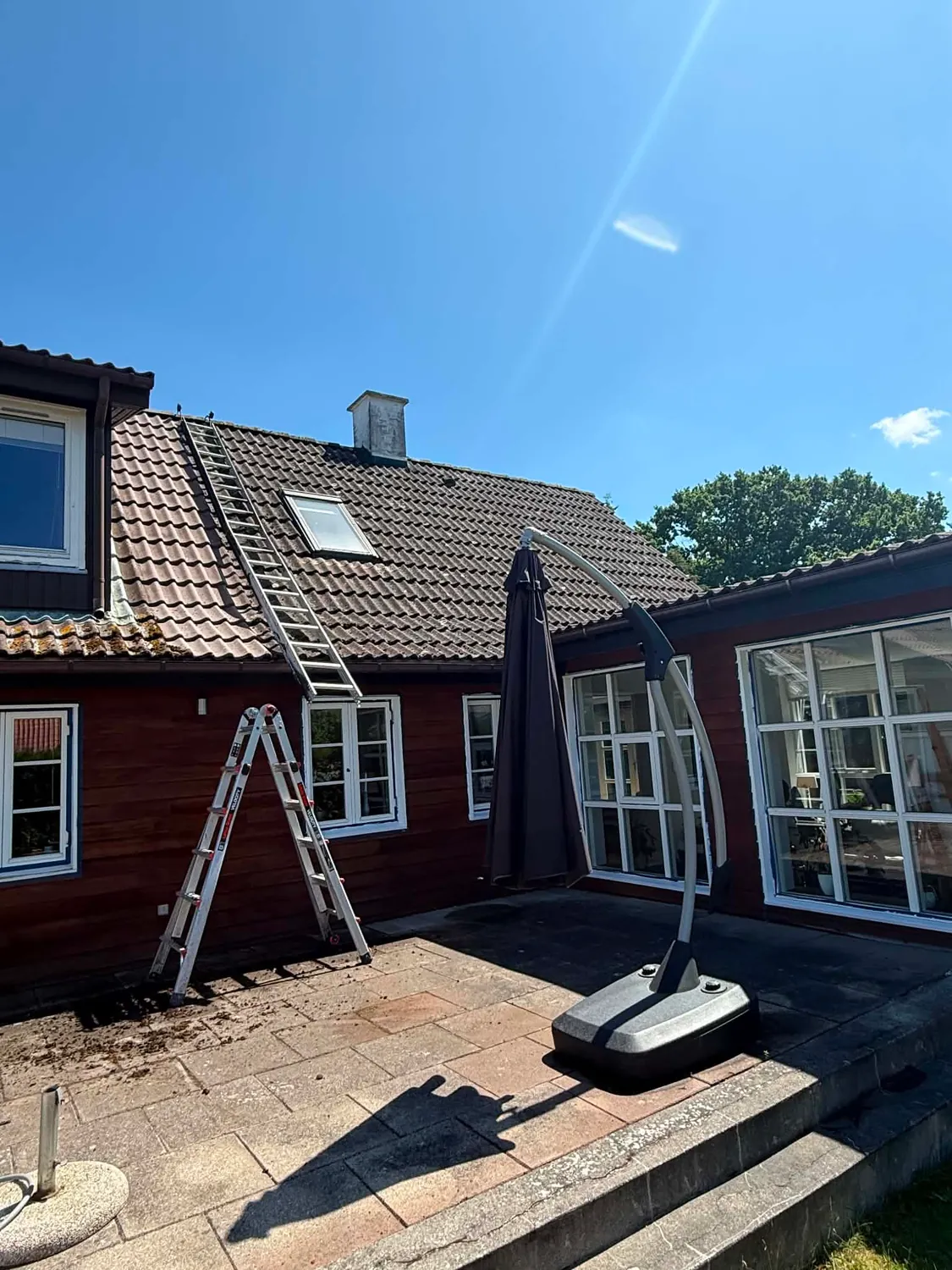 Tagstige op ad tagfladen og en trappestige ved facaden, mens mørkt mos og alger fra taget ligger spredt på terrassens fliser
