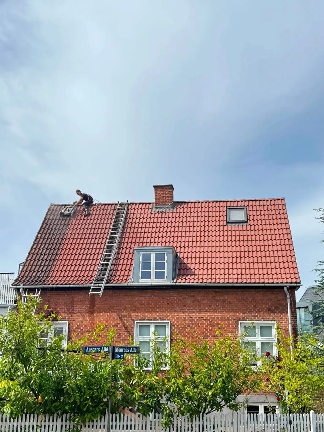 Villa med nyrenset rødt tegltag, hvor medarbejder og stige stadig står på taget